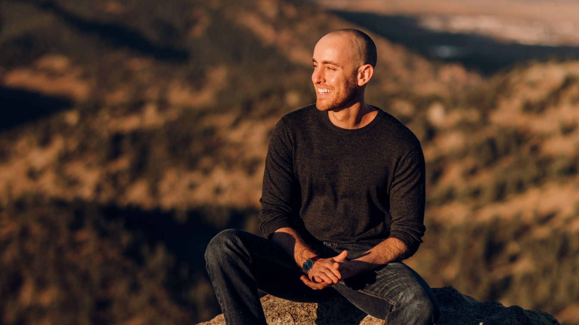 Jason sitting in a dark sweater at golden hour